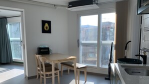 A modern kitchen with a large window, a dining table with chairs, and a black toaster. - Just Mansion (Seoul)