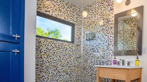 A bathroom with a colorful mosaic wall, a wooden vanity, and a large mirror. - Groovy!!! at Odonata Escape -- retro chic container room in the country (Fredericksburg)