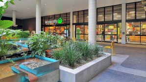 A shopping mall interior with a Woolworths store, indoor plants, and a water feature. - Comfy Character QLD’r ~ 3Bed House w/Parking (Woolloongabba)