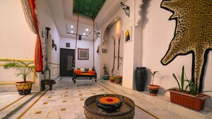 Un couloir avec un foyer central, des plantes en pot et un sol à motifs.