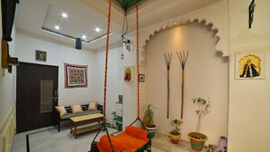 Une pièce comprenant un fauteuil suspendu, un canapé, un lit et un mur décoratif orné d’icônes religieuses.