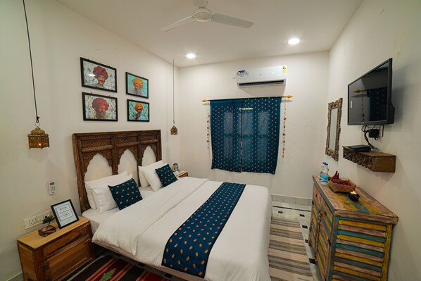 A bedroom with a bed, a dresser, a television, and wall decorations.