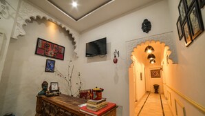 Un couloir avec un bureau en bois, des livres, des objets de décoration, un téléviseur et une statue de Bouddha.