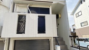 A two-story building with a garage door, a small balcony, and a staircase leading to the upper floor. - Kyo Yado Inari (Kyoto)