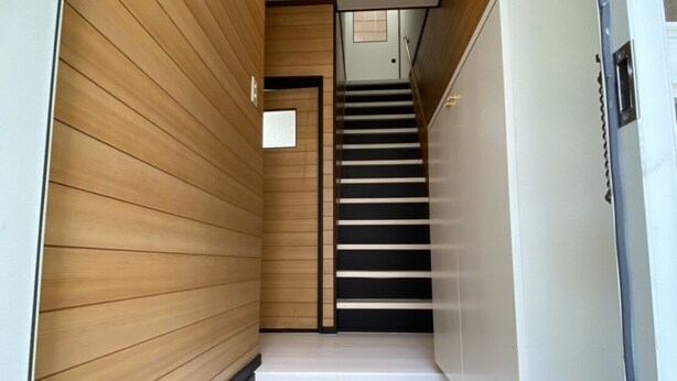 A narrow hallway with wooden panel walls, a tiled floor, a staircase, and a white refrigerator. - Kyo Yado Inari (Kyoto)