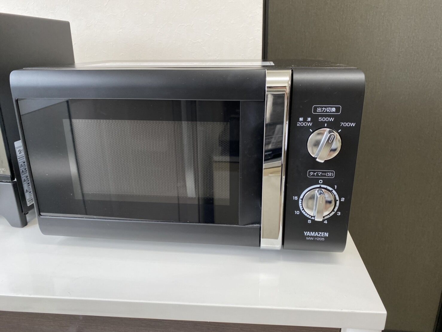 A black microwave oven with a digital display and control knobs on the right side.