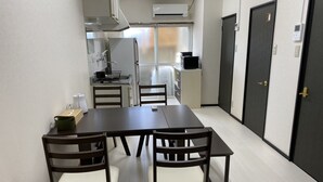 A compact kitchen with a dining table and chairs, a refrigerator, and a microwave. - Kyo Yado Inari (Kyoto)