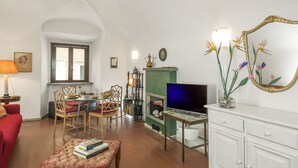 Ein Wohnzimmer mit Kamin, Fernseher, Essbereich mit Stühlen und einem roten Sofa.