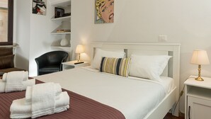 A hotel room with a large bed, two bedside tables, a chair, and artwork on the walls.