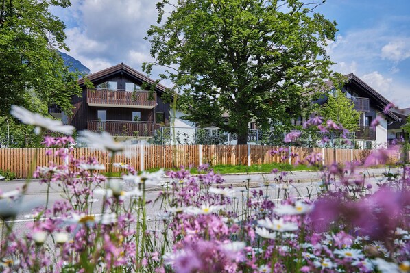 A residential area with houses, a wooden fence, and a tree. - Bader Suites (Garmisch-Partenkirchen)