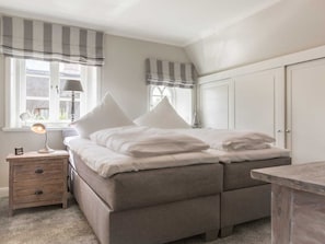 A bedroom with a double bed, a bedside table with a lamp, and a wardrobe.
