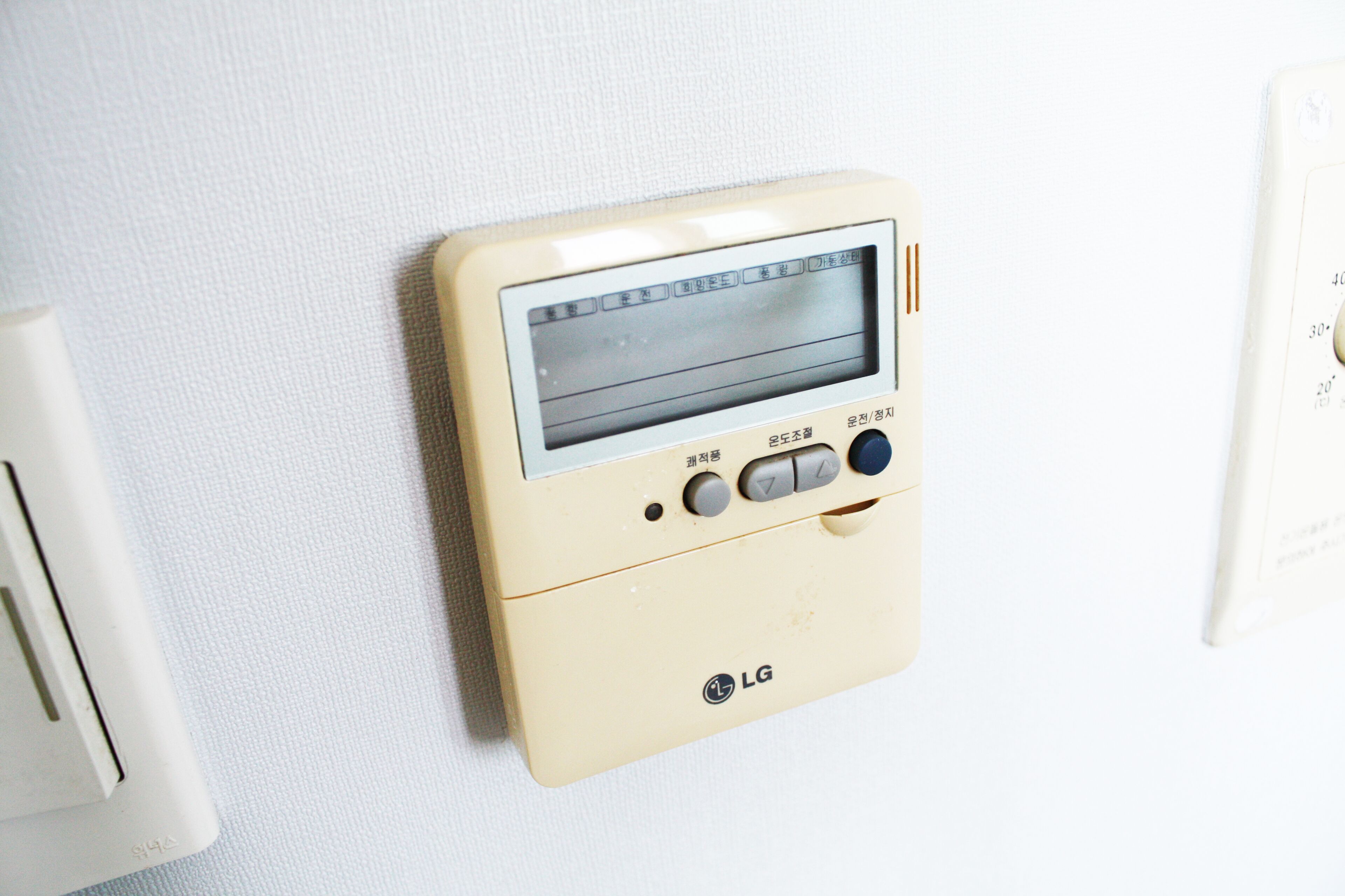 Termostato LG montado en la pared con pantalla digital y botones de control.