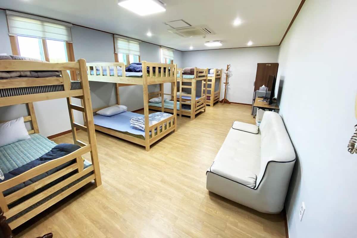 Une chambre de dortoir avec des lits superposés, un canapé blanc et un bureau avec un ordinateur.