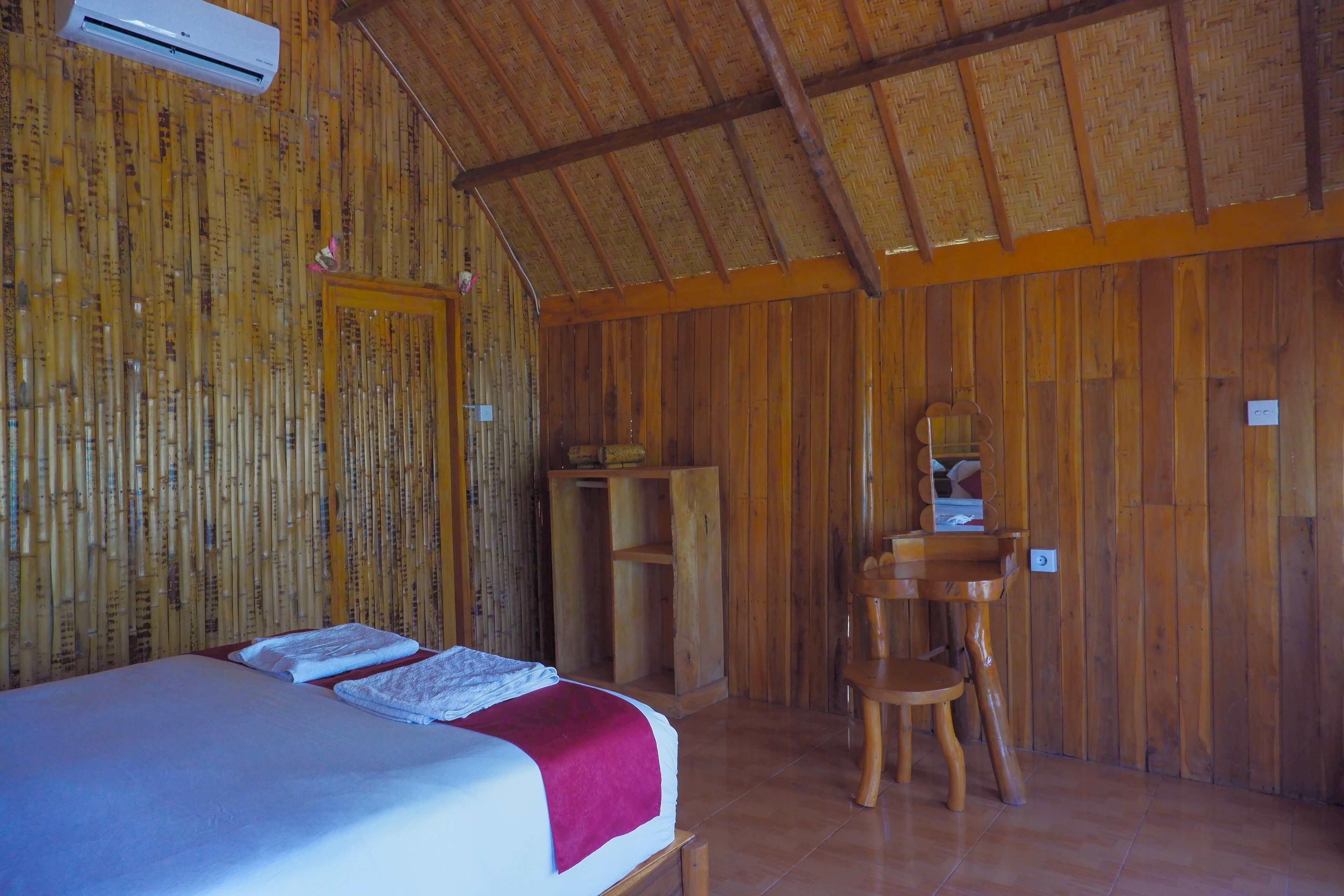 Une pièce comprenant un lit, une armoire en bois, une chaise et un miroir.