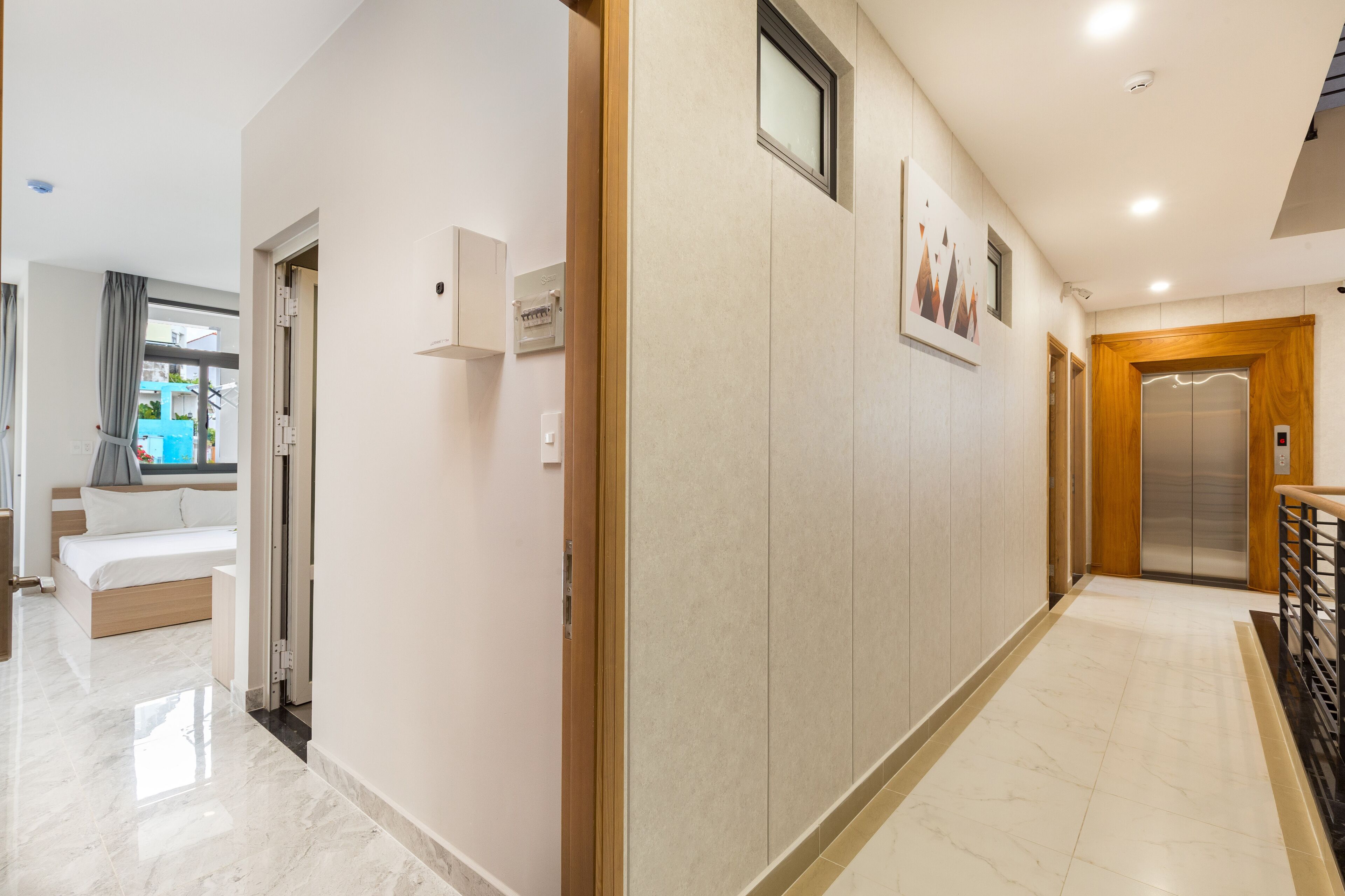 Un pasillo de hotel con una cama, una puerta y un ascensor.