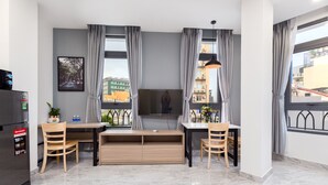 A modern living room with a large TV, a wooden dining table, and a built-in entertainment unit.