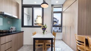 A modern kitchen with wooden cabinets, a white countertop, and a dining table with chairs.
