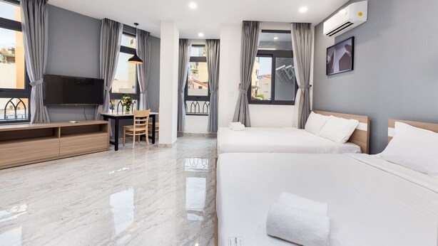A modern hotel room with a large bed, a desk, and a TV.