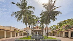 A courtyard with a central fountain, palm trees, and a building with a tiled roof. - Coma Villas Beach Da Nang (Da Nang)