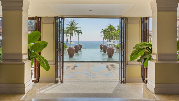 A hotel entrance with a view of a pool and palm trees. - Coma Villas Beach Da Nang (Da Nang)