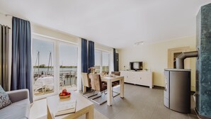 Un salon moderne comprenant un coin repas, une cuisine et donnant sur un port de plaisance.