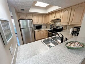 A kitchen with a stainless steel refrigerator, a microwave, a stove, and a sink.