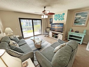 A living room with a sofa set, a television, and a ceiling fan.