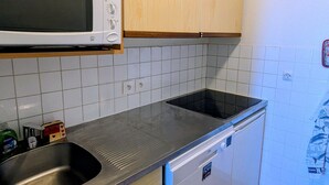 A kitchen with a microwave, stove, sink, and wooden cabinets.