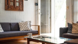 A living room with a sofa, a glass coffee table, and a door leading to a balcony.