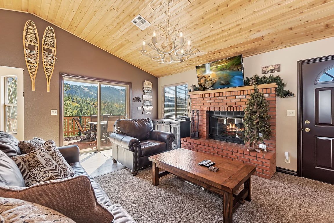 A cozy living room with a fireplace, leather sofa, and a view of the outdoors.