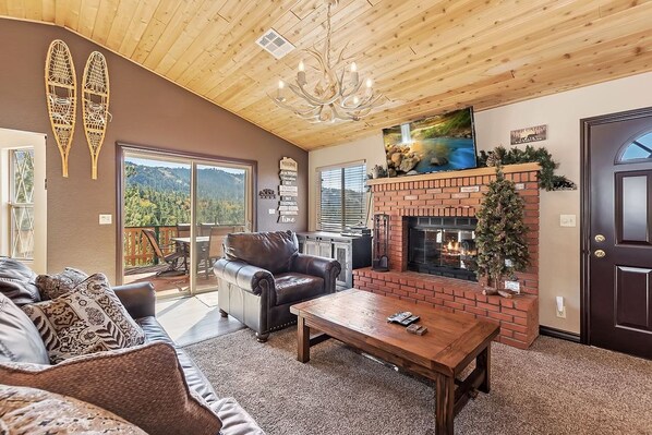 Una sala de estar acogedora con chimenea, sofá de cuero y vistas al exterior.