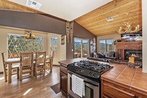 Una cocina con una estufa grande, una mesa de comedor de madera y sillas, con vista al exterior.