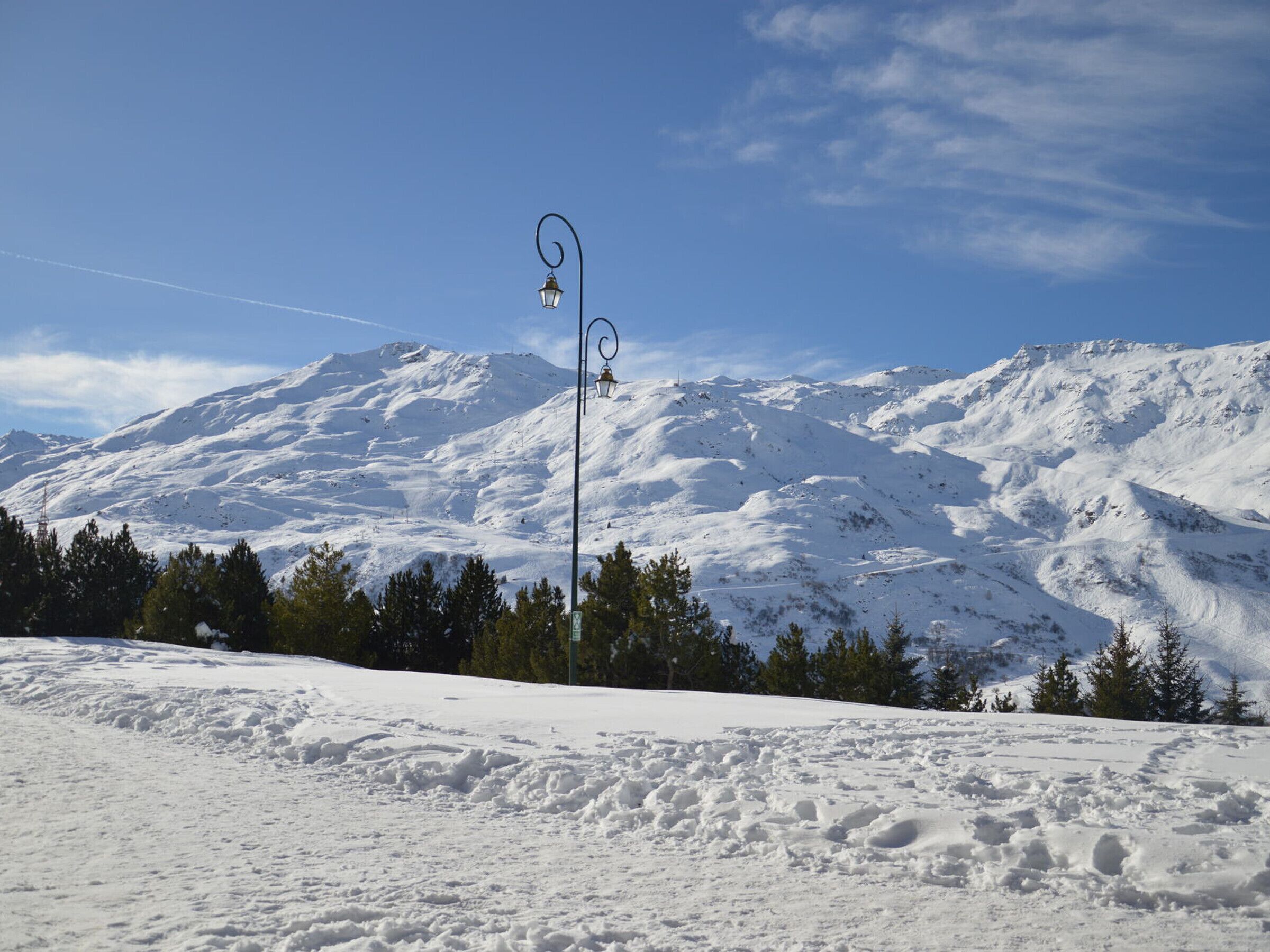 A snow-covered mountain landscape with a street lamp in the foreground.