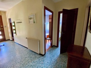 A hallway with a radiator, a door leading to a room, and a coat rack with keys.