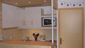 Une cuisine avec des meubles de rangement en bois, un four à micro-ondes, un évier et une machine à café.