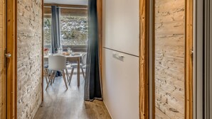 A narrow hallway with wooden walls and a dining area visible through a window. - Renovated Studio 4 pax - Ski-in/Ski-out with WiFi (Tignes-Le Lavachet)