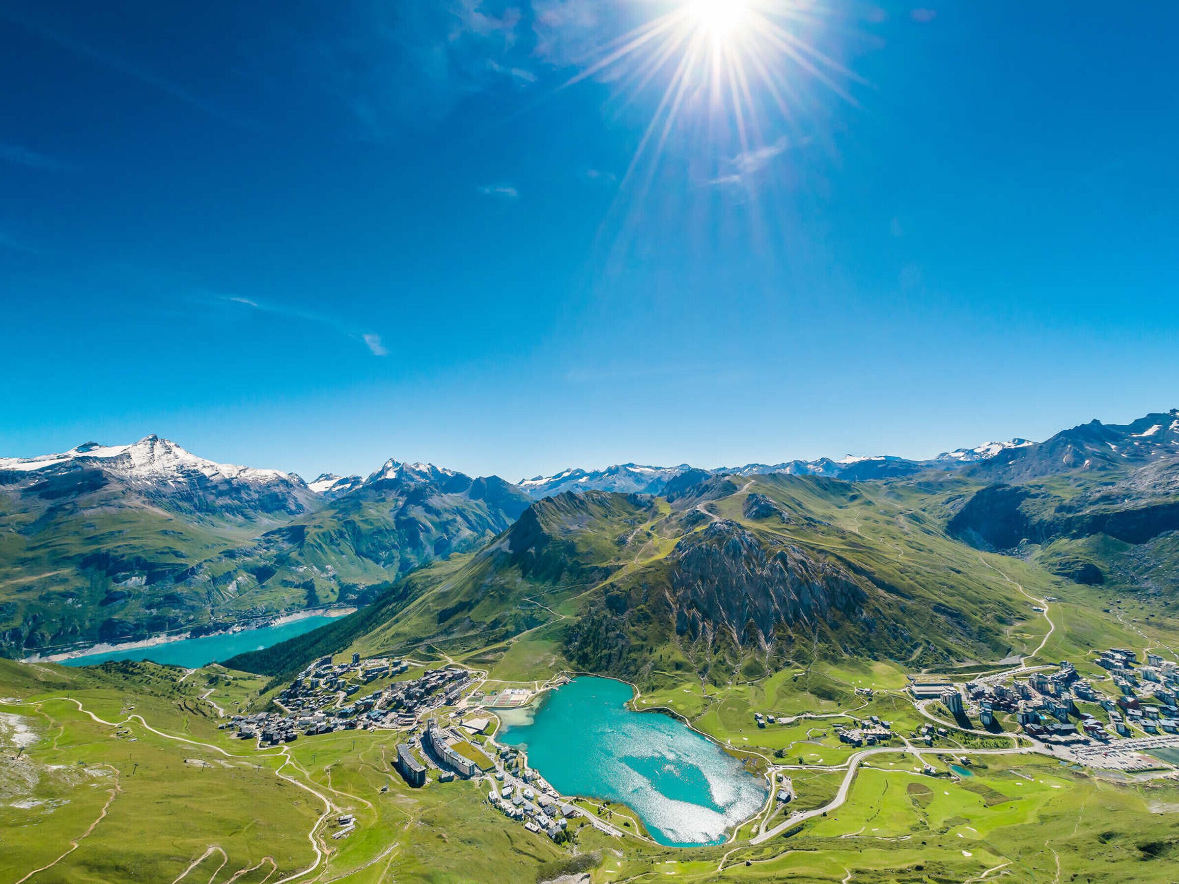 A mountainous landscape with a lake, a small town, and a clear sky.