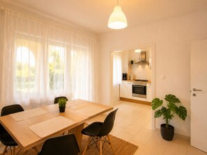 A modern kitchen with white cabinets, a stove, and a coffee maker.