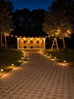 A pathway leading to a building with string lights and a ladder.