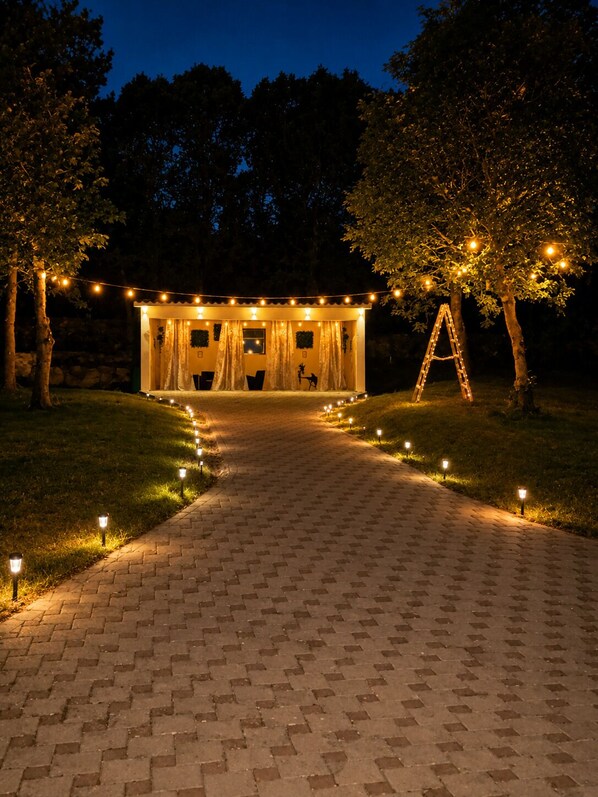A pathway leading to a building with string lights and a ladder.