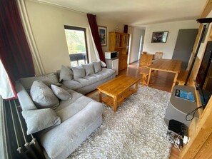 A living room with a grey sectional sofa, a wooden coffee table, and a TV stand with a flat-screen TV.