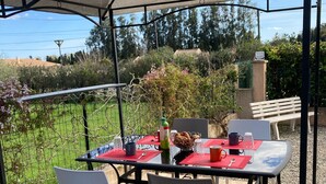A covered outdoor dining area with a table set for two, surrounded by chairs, and a bench in the background. - Charming villa for 4 people, private pool between sea and mountains  (Aléria)