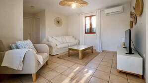 A modern living room with a sofa, a coffee table, a TV stand, and a decorative wall piece. - Charming villa for 4 people, private pool between sea and mountains  (Aléria)
