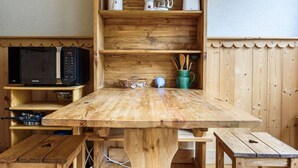 Une table en bois avec un four à micro-ondes et une machine à café placés sur des étagères au-dessus.
