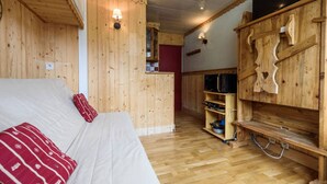 Une pièce en bois comprenant un lit, une armoire en bois et un petit coin cuisine.