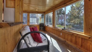 A wooden-paneled room with a bed, a heater, and large windows. - 🐾Lakeview on Main - Located in the village of Rangeley with water views! Dog Friendly (Rangeley)