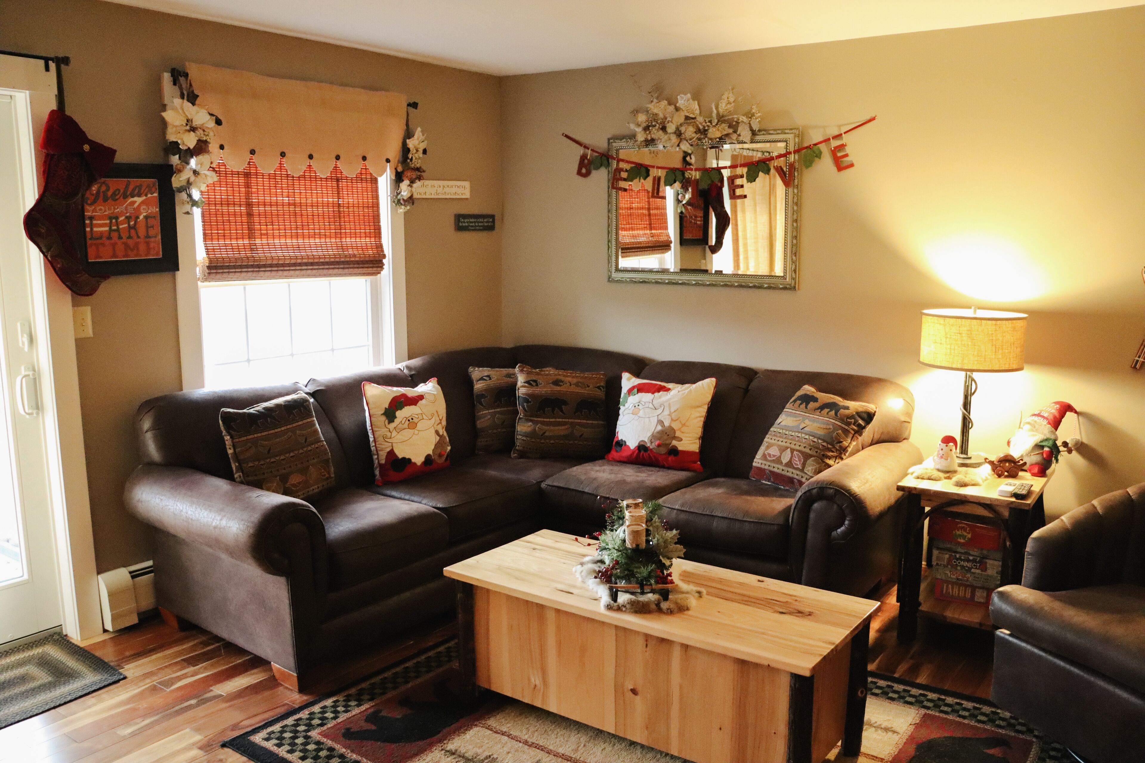 A cozy living room with a brown leather sofa, a wooden coffee table, and a small Christmas tree.