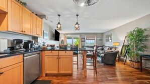 A spacious kitchen with wooden cabinets, a dishwasher, and a dining area with a sofa and chairs. - Town Park Condo D - Great central location in the center of downtown Rangeley (Rangeley)
