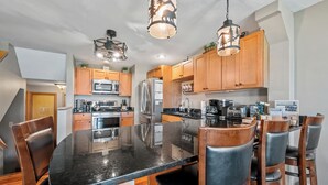 A modern kitchen with wooden cabinets, stainless steel appliances, and a black marble countertop. - Town Park Condo D - Great central location in the center of downtown Rangeley (Rangeley)