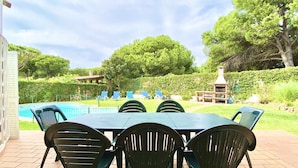Une terrasse avec piscine, un espace salon extérieur et un coin barbecue.